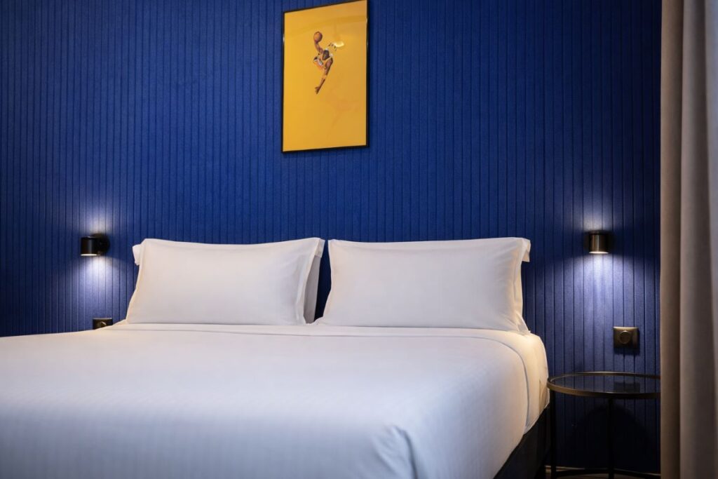 Lit double avec tête de lit bleue et appliques noires, chambre double du ClapClap Hotel à Strasbourg