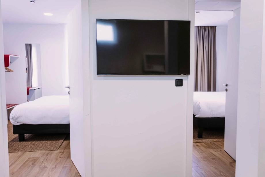 Deux chambres communicantes avec lits doubles et télévision murale à l’Hôtel Clapaclap Strasbourg