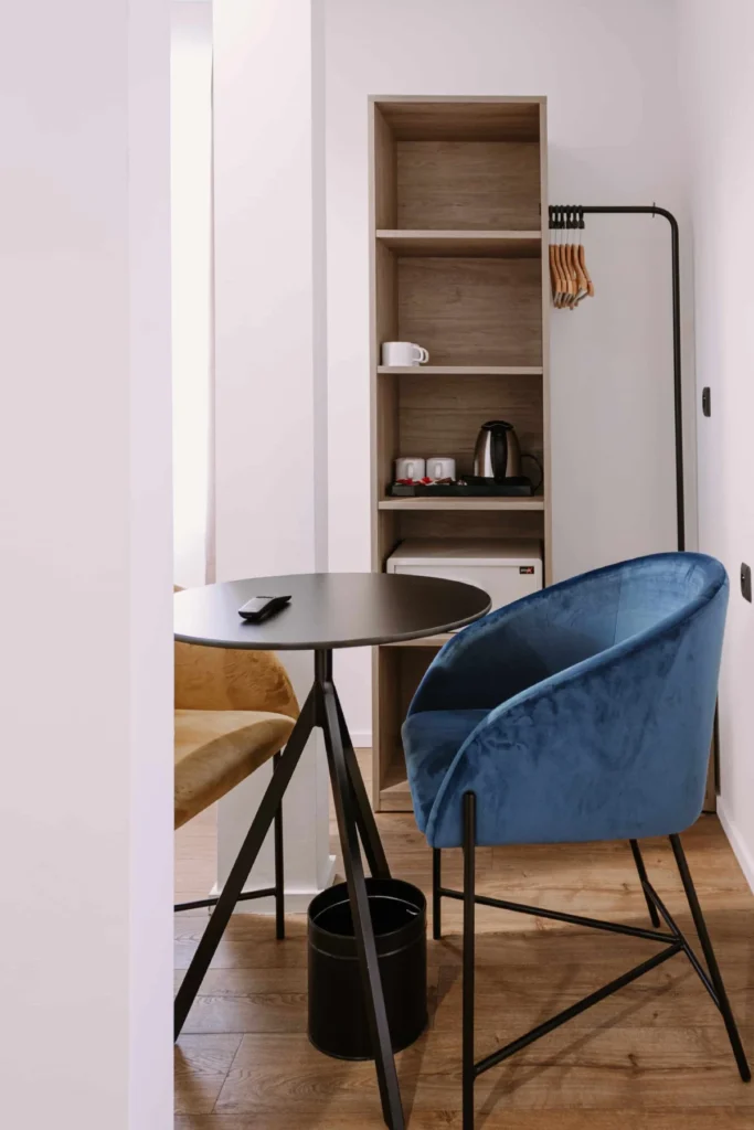 Chambre Famille 6 personnes du ClapClap Hôtel Strasbourg avec fauteuil velours bleu, table ronde noire, étagère en bois et bouilloire