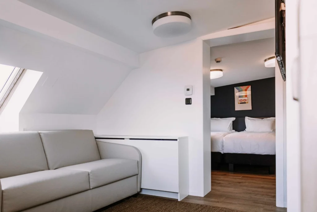 Chambre Tribu du ClapClap Hôtel Strasbourg avec salon canapé et chambre avec lit double en enfilade