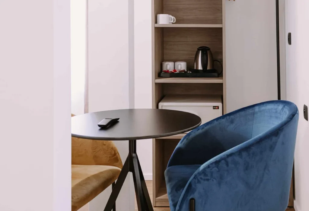 Chambre Famille 6 personnes du ClapClap Hôtel Strasbourg avec fauteuil velours bleu, table ronde noire, étagère en bois et bouilloire