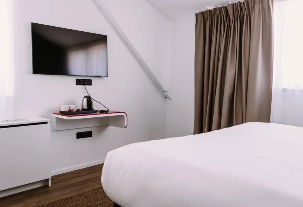 Chambre Tribu du ClapClap Hôtel Strasbourg avec lit, TV murale, étagère rouge et velux