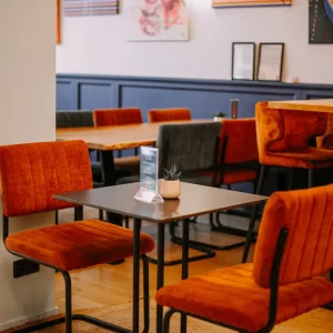 ClapShow-Saal im ClapClap Hotel Straßburg mit orangefarbenen Samtsesseln, schwarzen Tischen und Kunstwerken an den Wänden