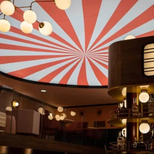 Plafond rayé rouge et blanc style cirque avec lustre globe doré au bar du Clap Show Strasbourg