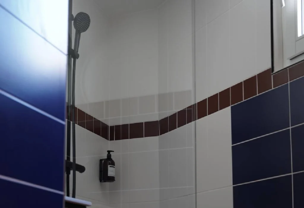 Douche du ClapClap Hôtel Strasbourg avec carrelage bleu cobalt, frise bordeaux et colonne de douche noire