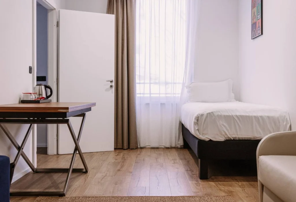 Chambre Tribu du ClapClap Hôtel Strasbourg avec lit, bureau en bois, bouilloire et affiche colorée