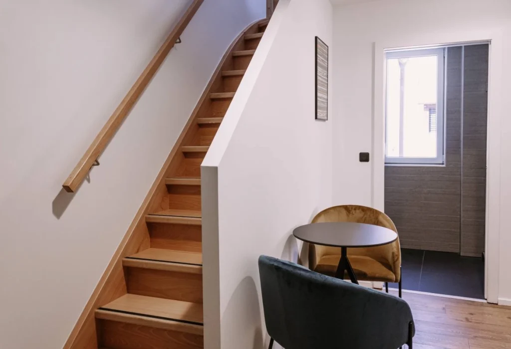 Chambre Tribu du ClapClap Hôtel Strasbourg avec escalier en bois, fauteuils velours et table ronde noire