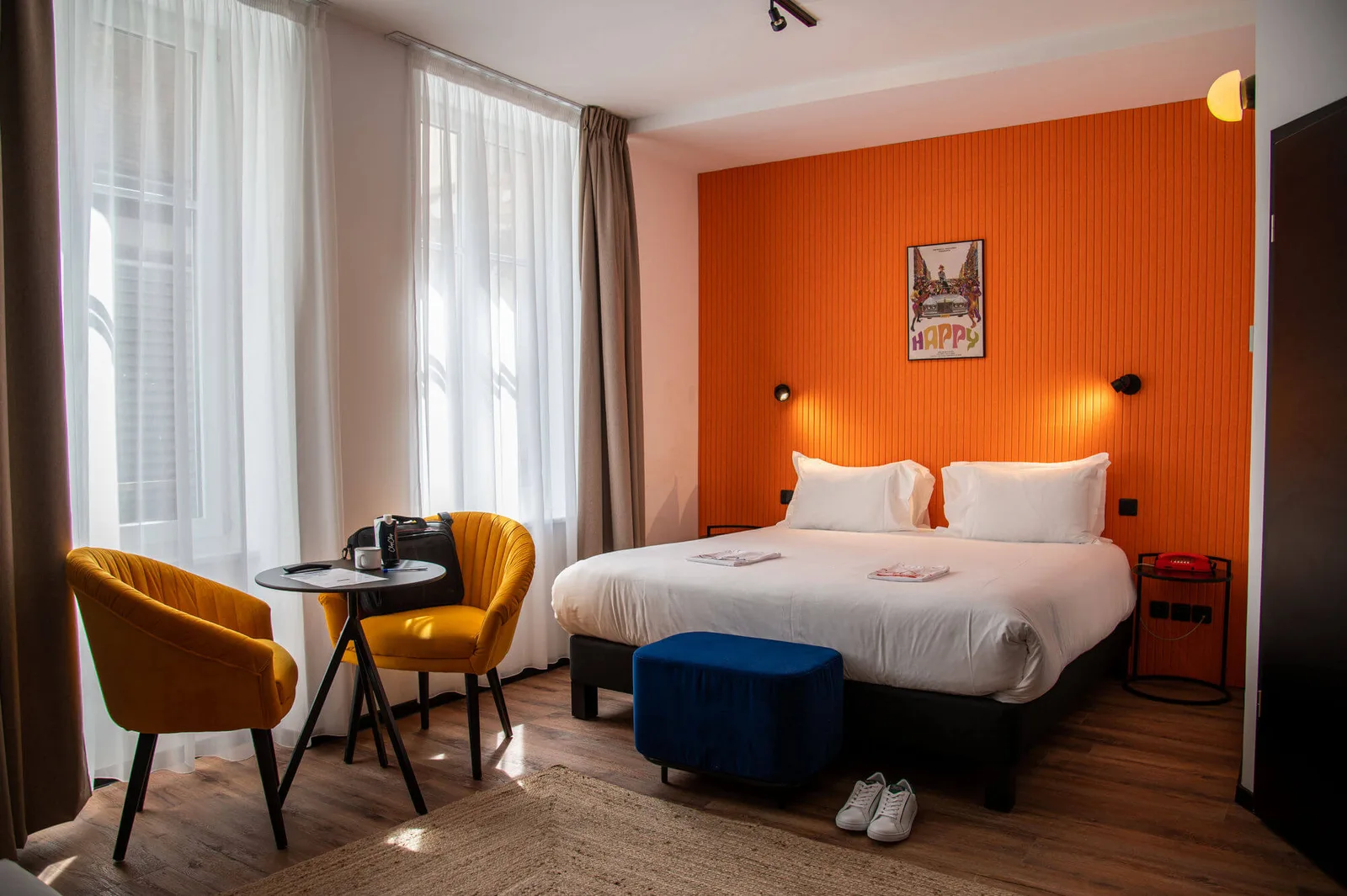 Doppelzimmer im ClapClap Hôtel in Straßburg mit orangefarbener Wand und gelben Sesseln