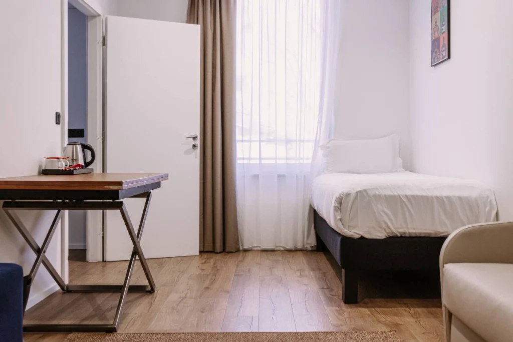 Chambre Tribu du ClapClap Hôtel Strasbourg avec lit, bureau en bois, bouilloire et affiche colorée